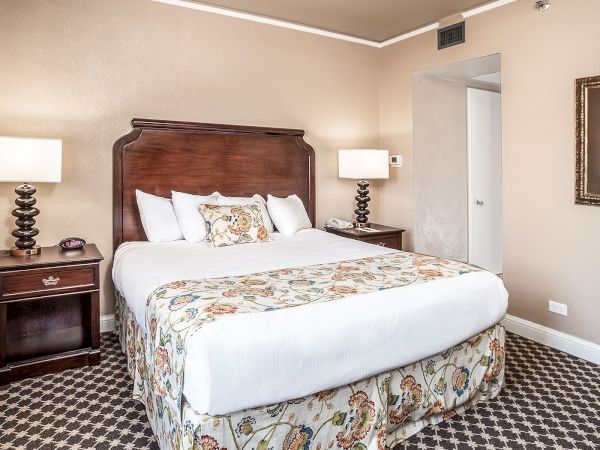 A neatly arranged hotel room with a bed, nightstands, lamps, and artwork on the wall featuring a cactus, creating a cozy atmosphere.