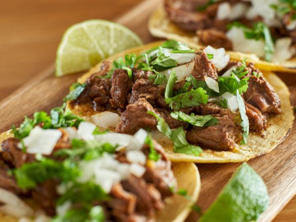 Delicious looking tacos with juicy beef, cilantro, onions, and lime wedges on soft tortillas&mdash;savory street-food vibes.